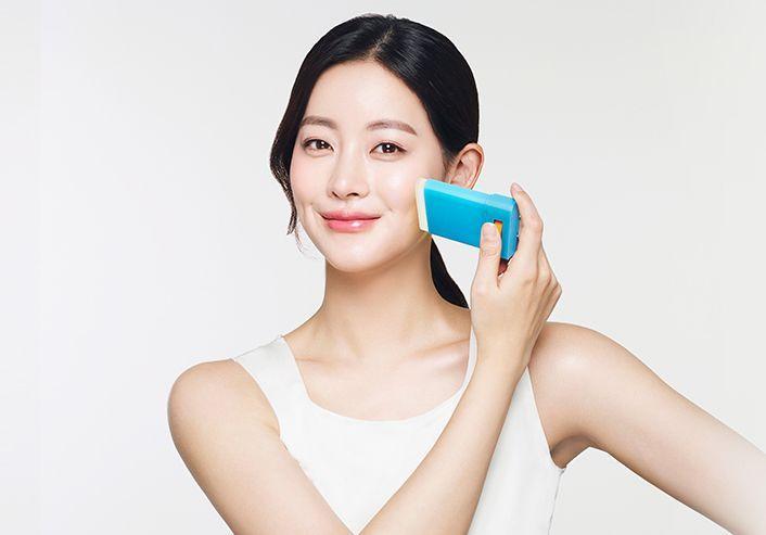 Young woman applying AHC Natural Perfection Fresh Sun Stick to her face, demonstrating how to use sun protection for daily skincare.